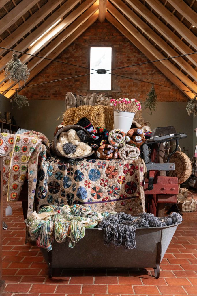 A display of hand-knitted and crochet blankets, wooden knitting needles and balls of rough-spun wool in the Jonkershuis Farm Shop at Soetmelksvlei.